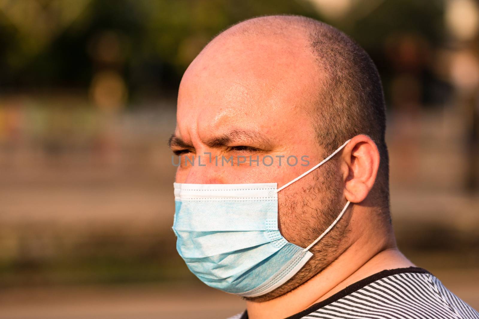Young man with medical protective face mask illustrates pandemic coronavirus disease on blurred background. SARS-CoV-2 outbreak in Europe. Changes and complications caused by epidemic