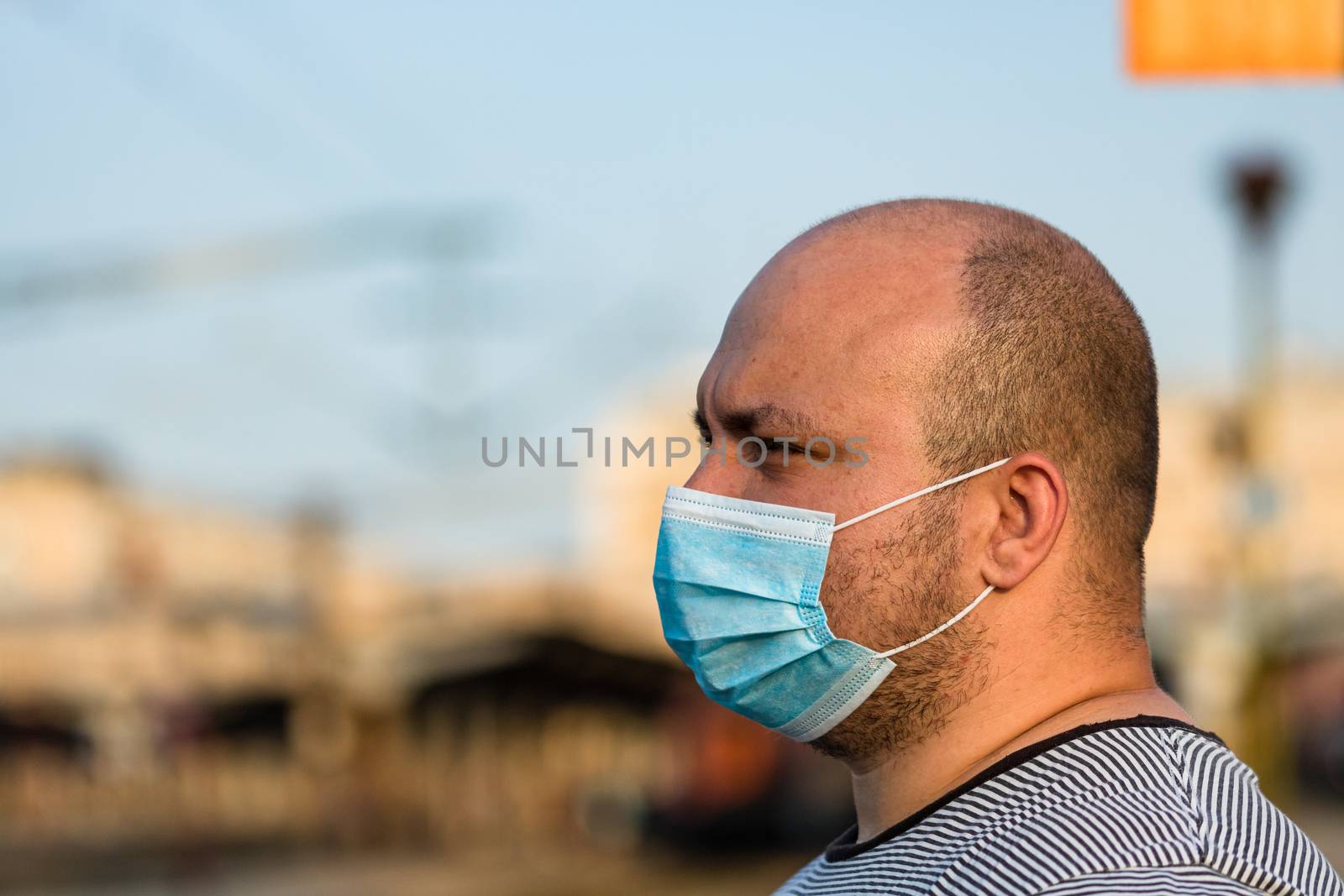 Young man with medical protective face mask illustrates pandemic by vladispas