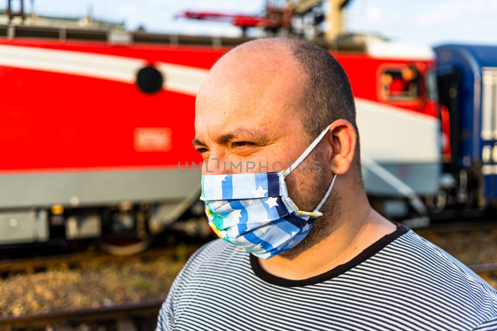 Young man with medical protective face mask illustrates pandemic coronavirus disease on blurred background. SARS-CoV-2 outbreak in Europe. Changes and complications caused by epidemic