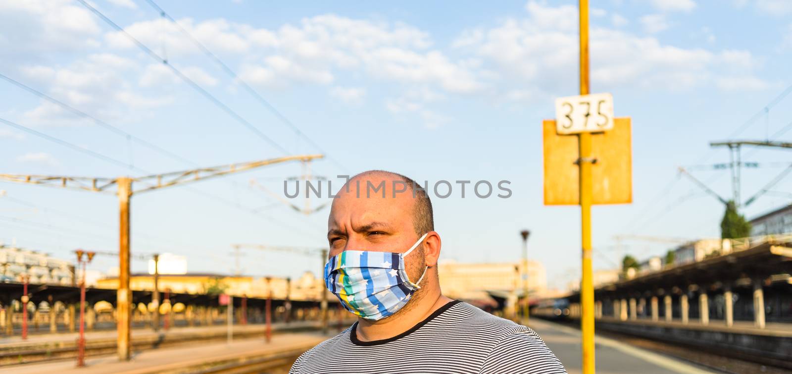 Young man with medical protective face mask illustrates pandemic coronavirus disease on blurred background. SARS-CoV-2 outbreak in Europe. Changes and complications caused by epidemic