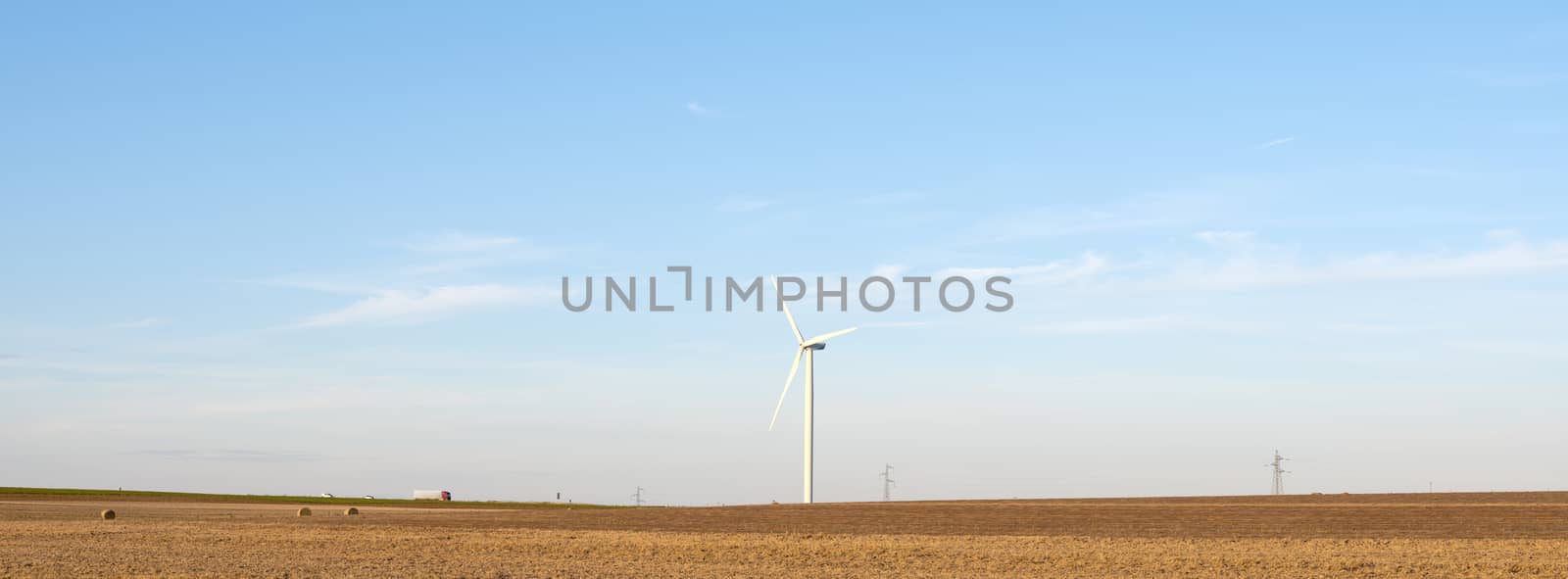 fields after harvest in the north of france with wind turbines in the background by ahavelaar