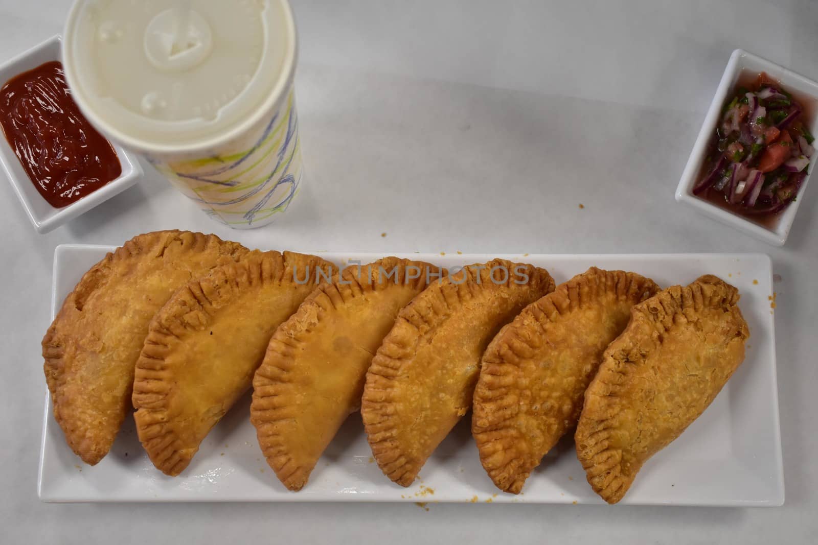 Golden Crispy Empenadas on a Long Plate on a White Background