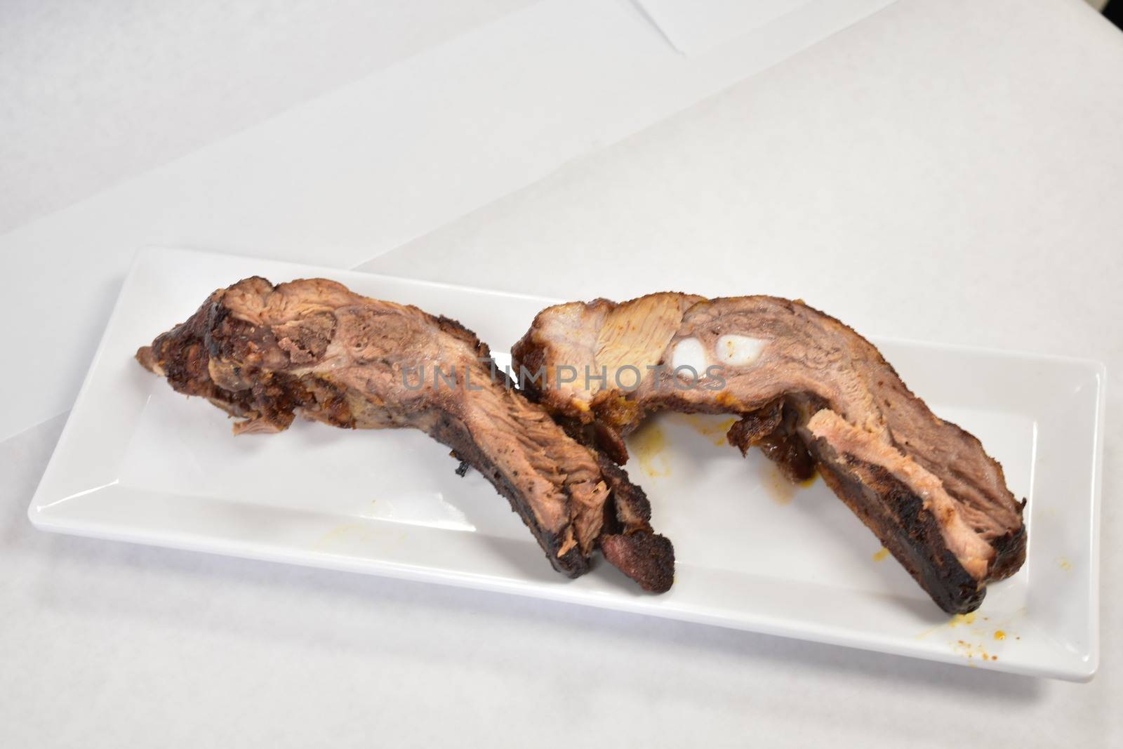 Two Well-Done Ribs Plated on a White Background