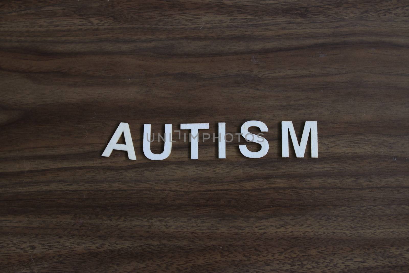 the word autism spelled out on a wooden background by mynewturtle1