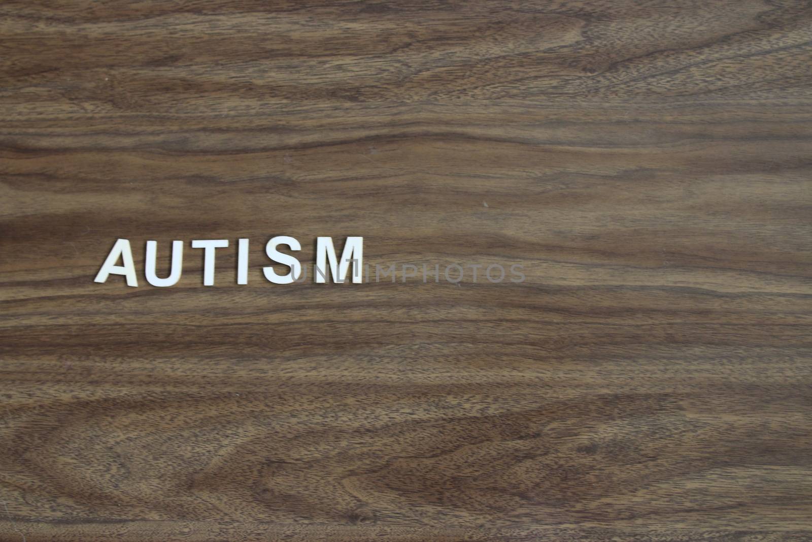 the word autism spelled out on a wooden background by mynewturtle1