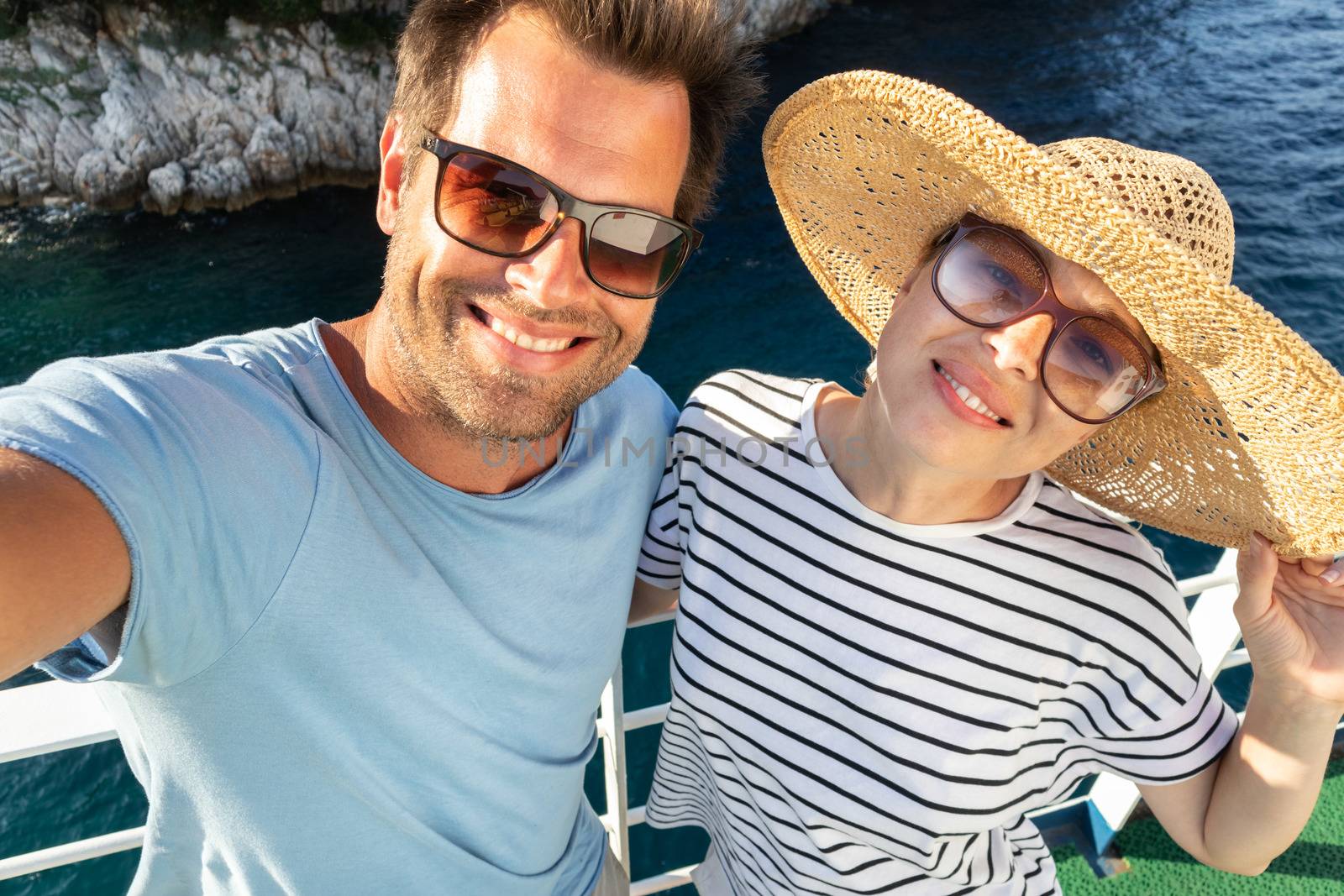 Beautiful, romantic caucasian couple taking selfie self portrait photo on summer vacations traveling by cruse ship ferry boat. by kasto