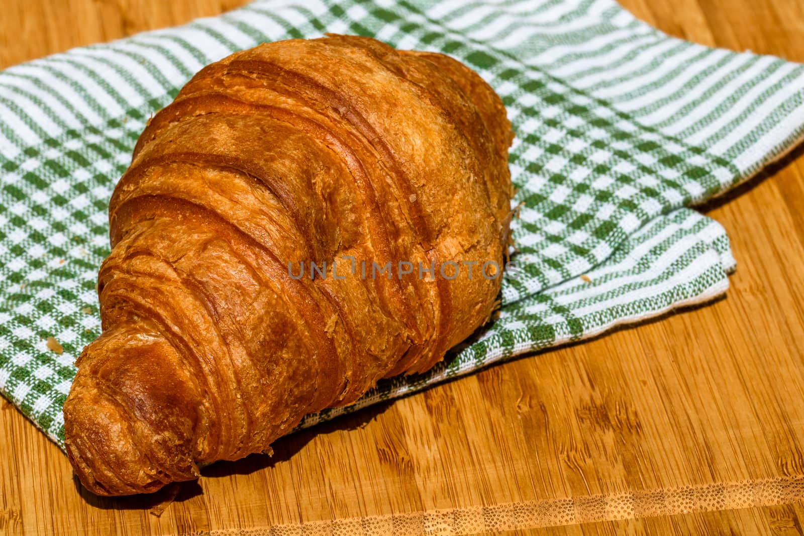 Detail of fresh croissant on wooden table. Food and breakfast concept. Close up photo of French buttery croissant