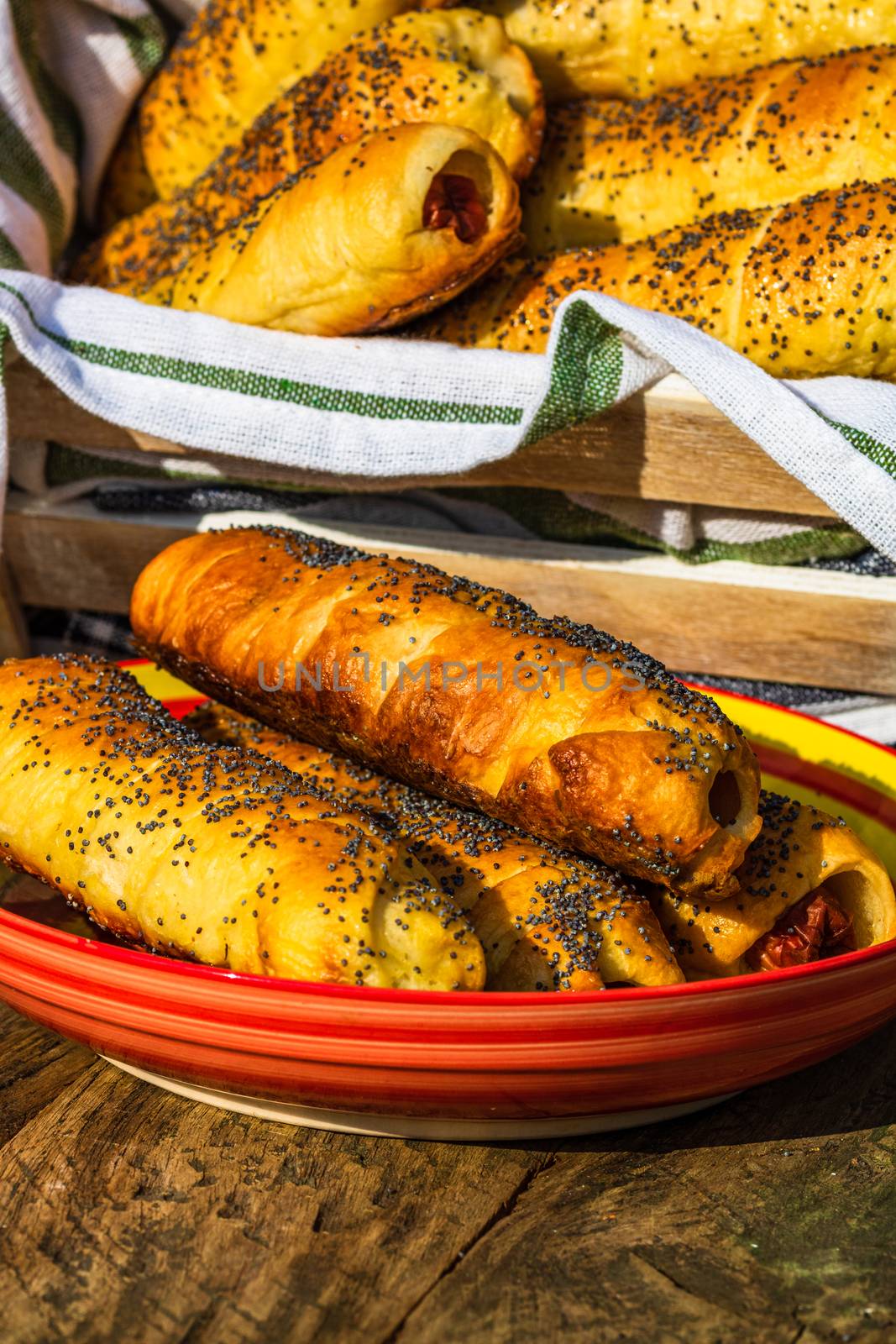 Sausages baked in dough sprinkled with salt and poppy seeds in a by vladispas