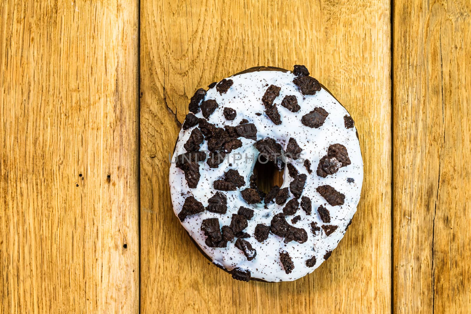 Colorful donuts on wooden table. Sweet icing sugar food with glazed sprinkles, doughnut with chocolate frosting. Top view with copy space