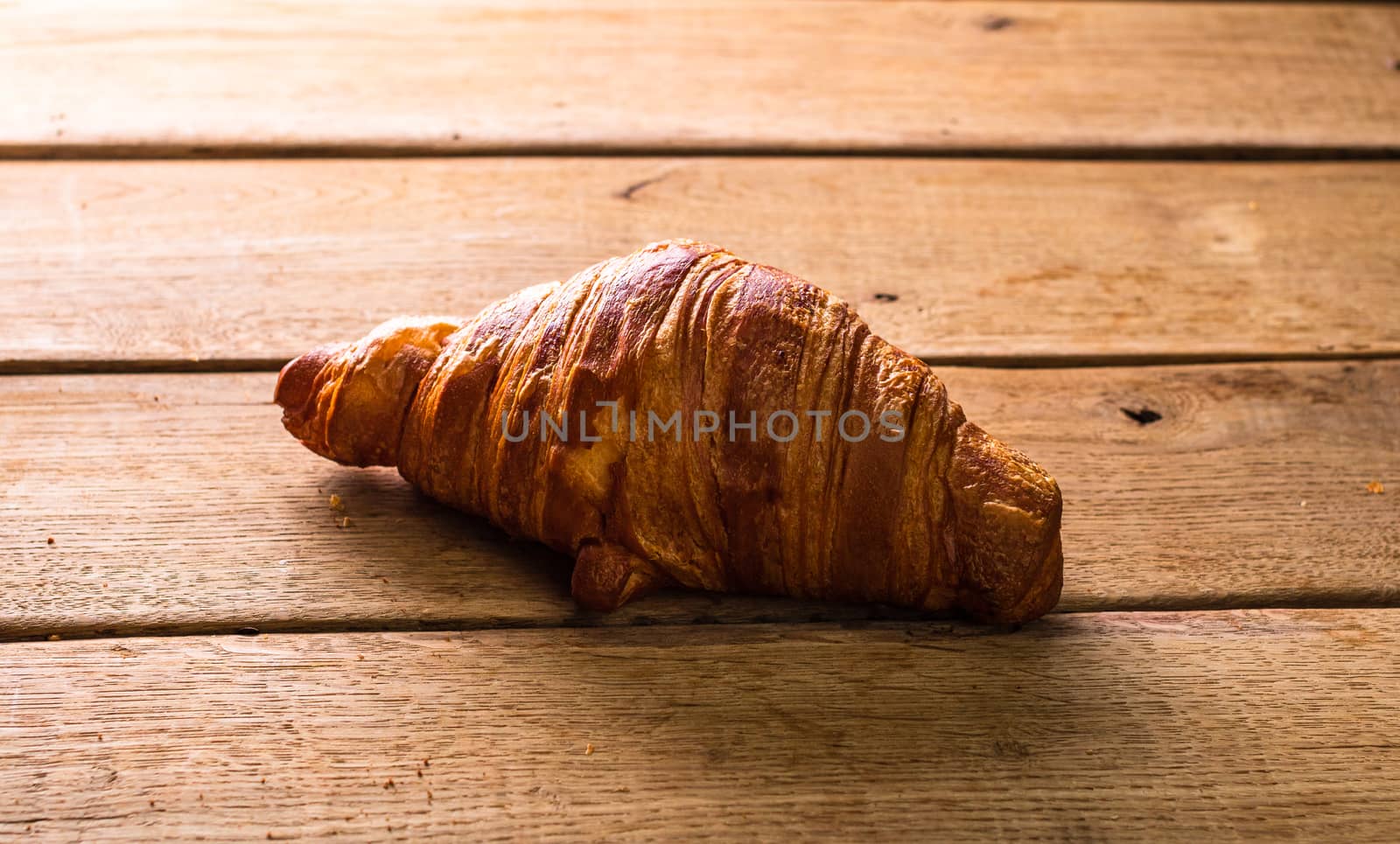 Detail of fresh croissant on wooden table. Food and breakfast co by vladispas