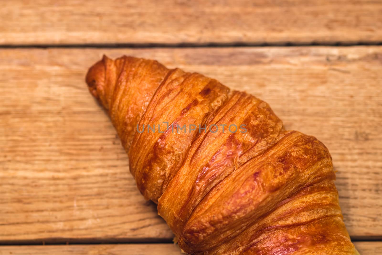 Detail of fresh croissant on wooden table. Food and breakfast co by vladispas