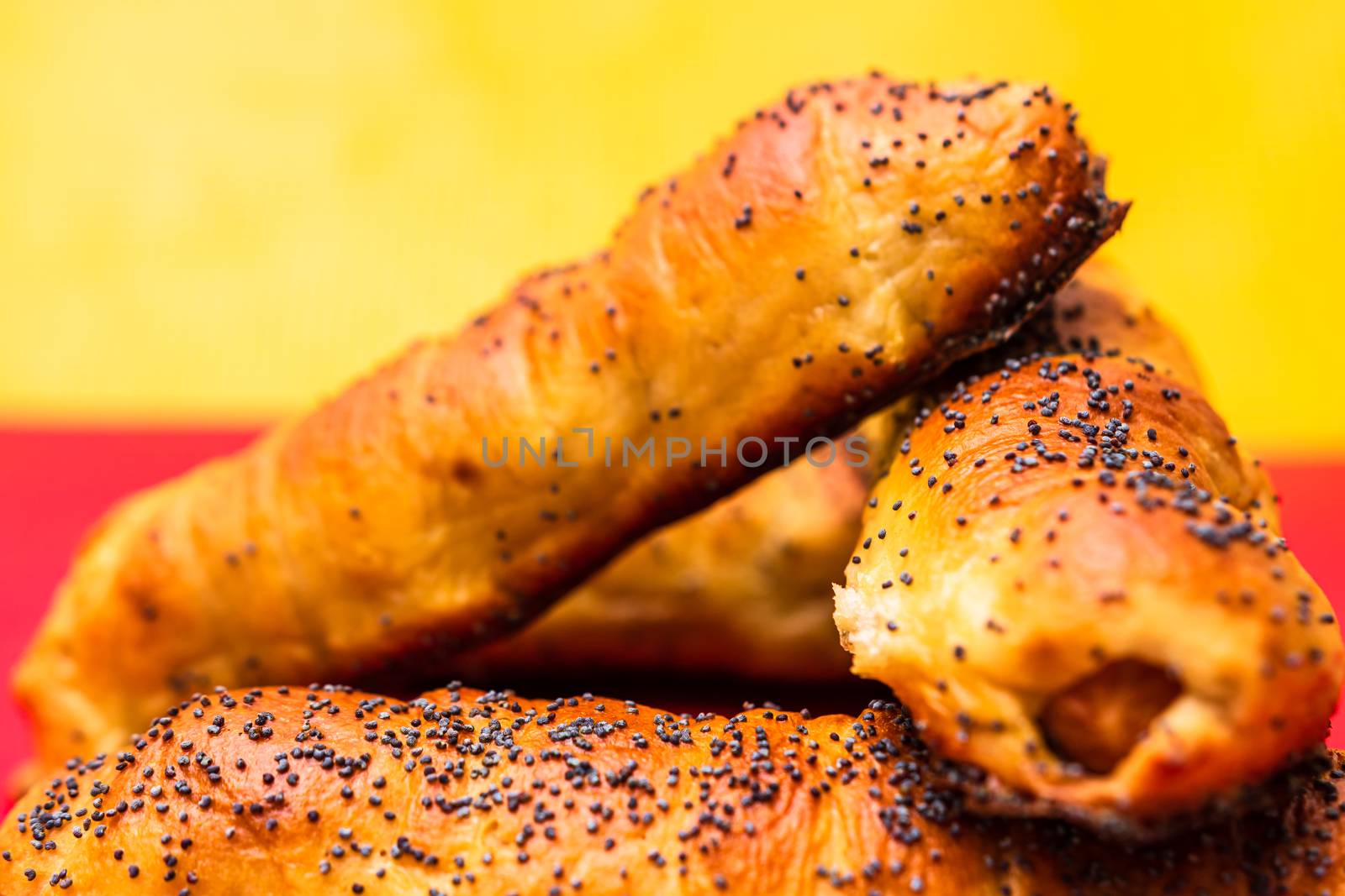 Close up of sausages baked in dough sprinkled with salt and poppy seeds. Sausages rolls, delicious homemade pastries isolated.