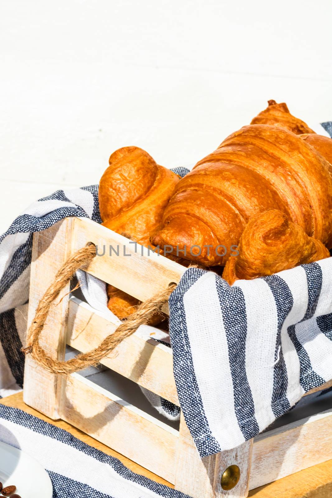 Fresh croissant, puff pastry and buttered french croissant on wooden crate. Food and breakfast concept. Detail of desserts and fresh pastries