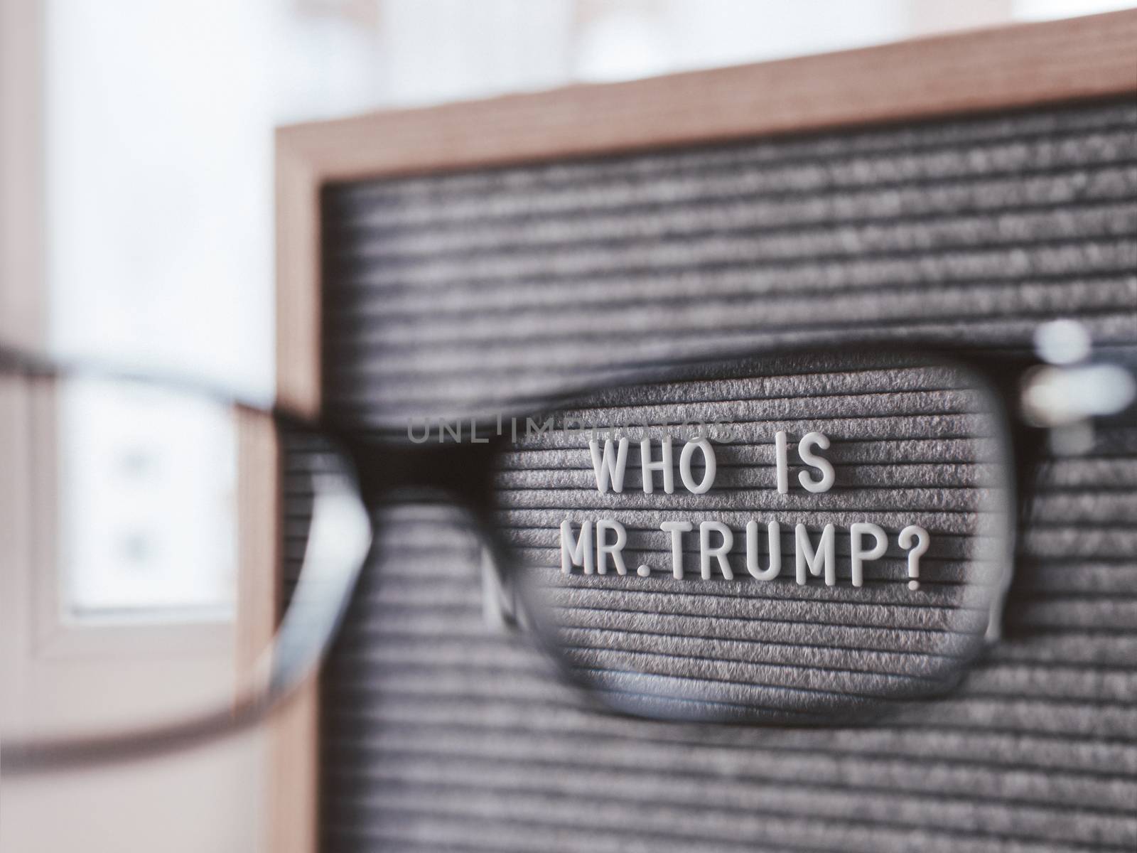 Letterboard with question WHO IS MR.TRUMP? through eyeglasses. Concept of political situation. Social issue. Closer look at the past of the USA President before the elections.