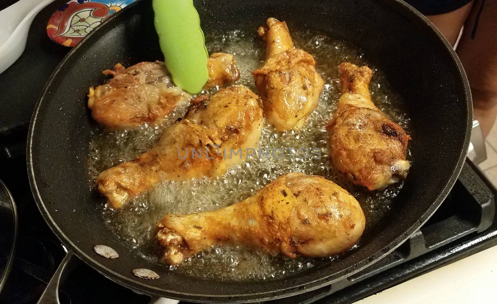 chicken drumsticks cooking in hot oil in frying pan on stove