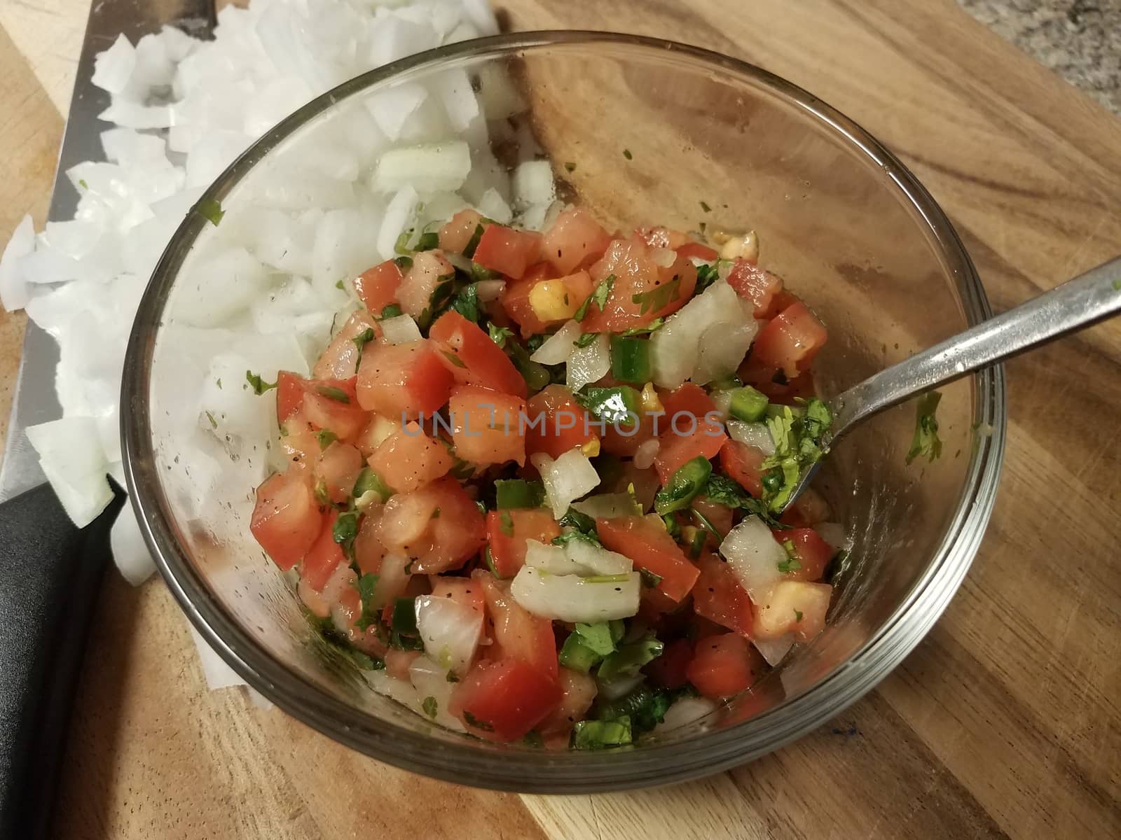 tomatoes and onions and glass bowl on wood cutting board