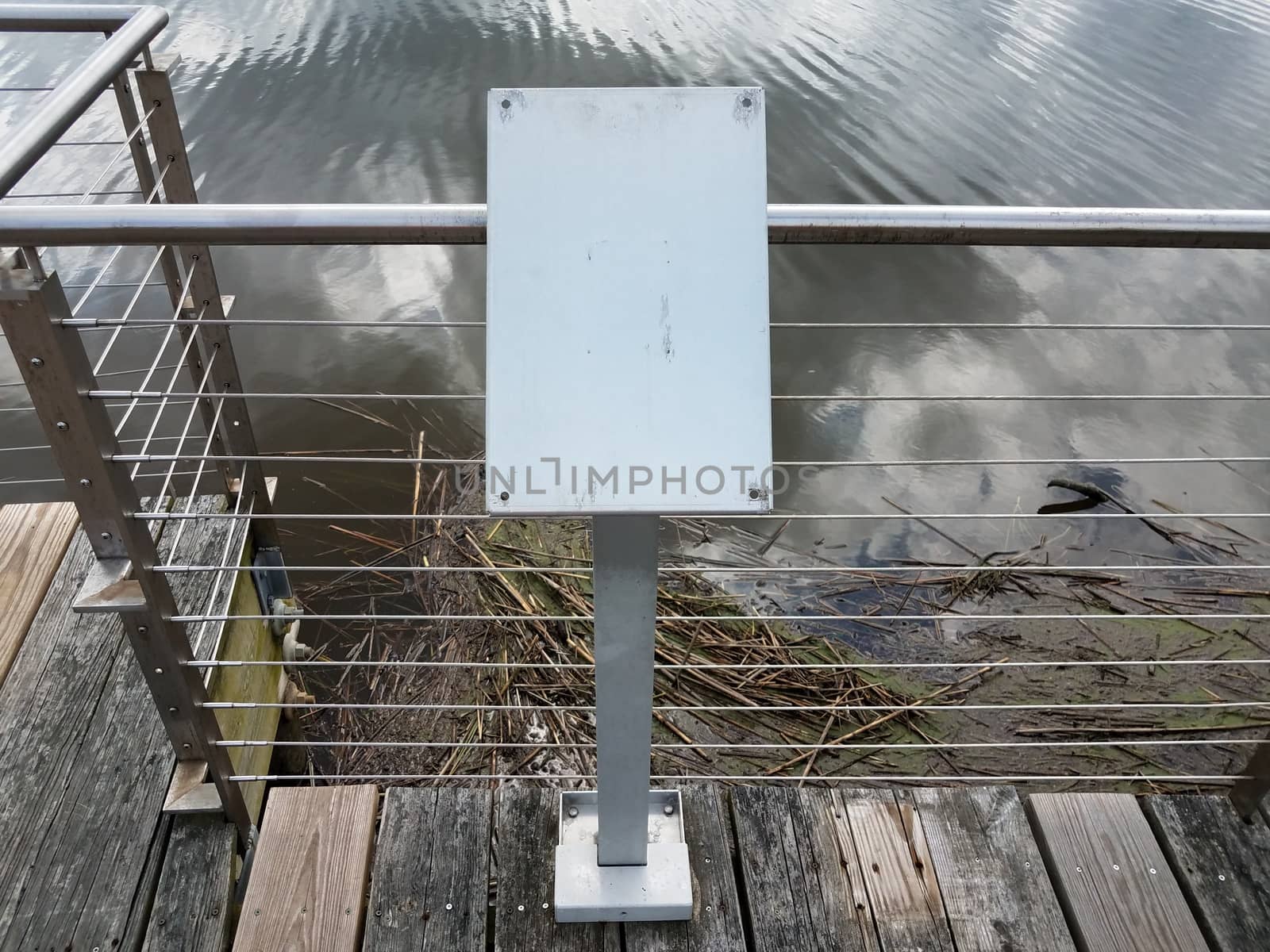 blank and worn metal plaque on railing with river water by stockphotofan1