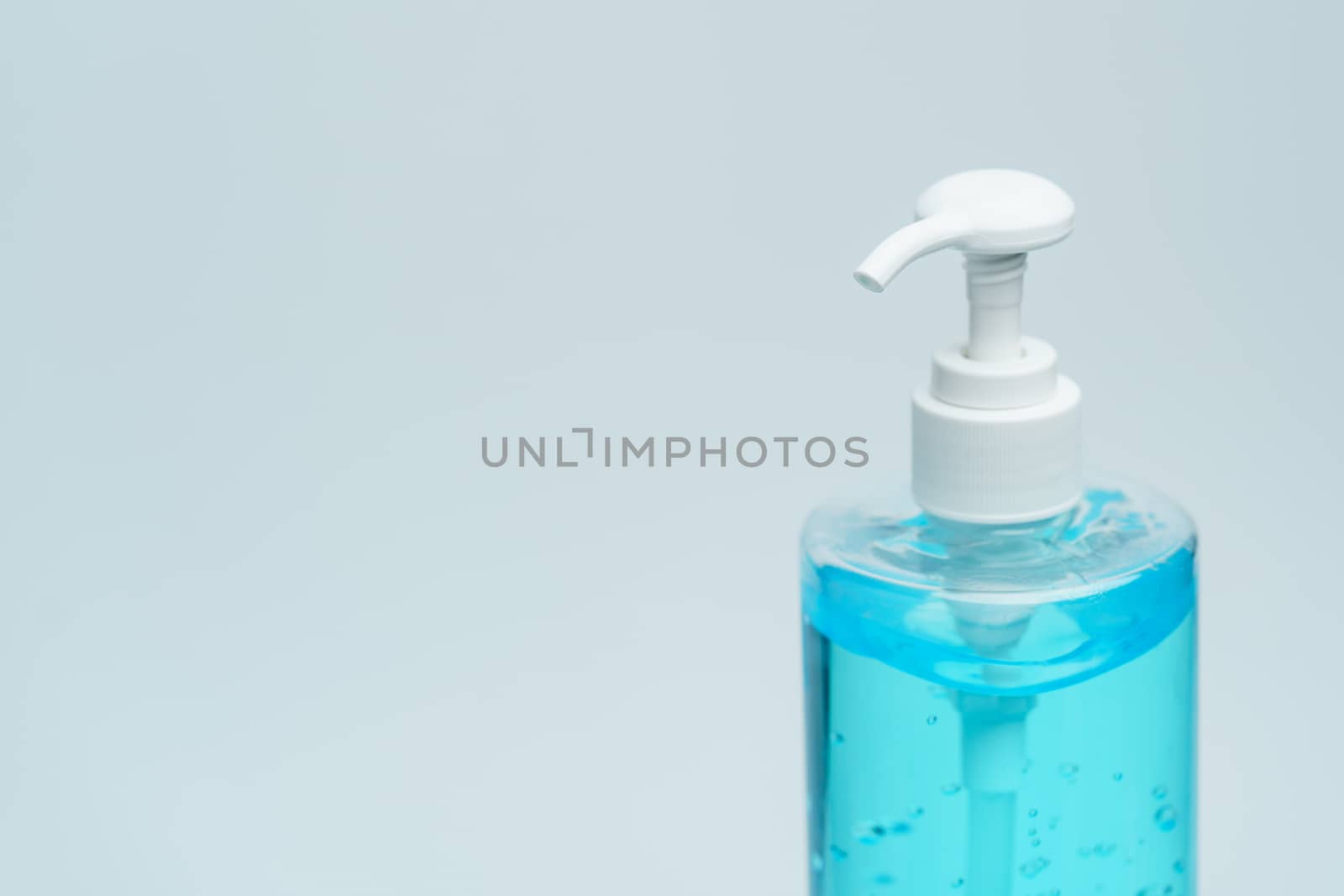 Clear blue hand sanitizer in a clear pump bottle on a white back by sirawit99