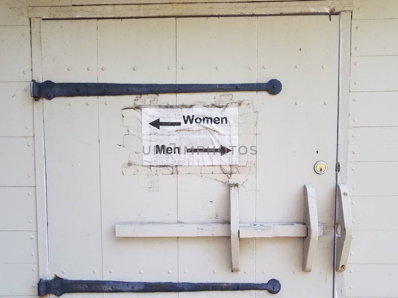 wood door with men and woman restroom sign and arrows by stockphotofan1