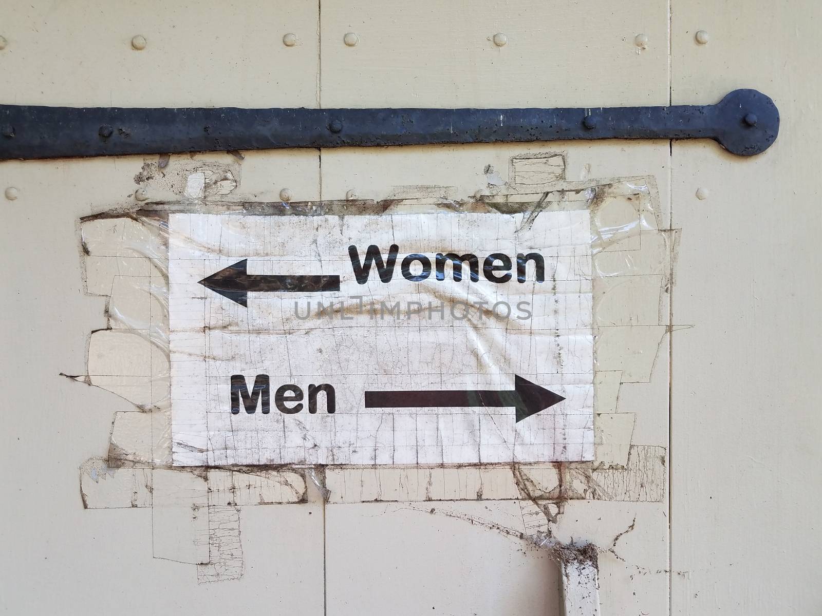 white wood door with men and woman bathroom sign and arrows