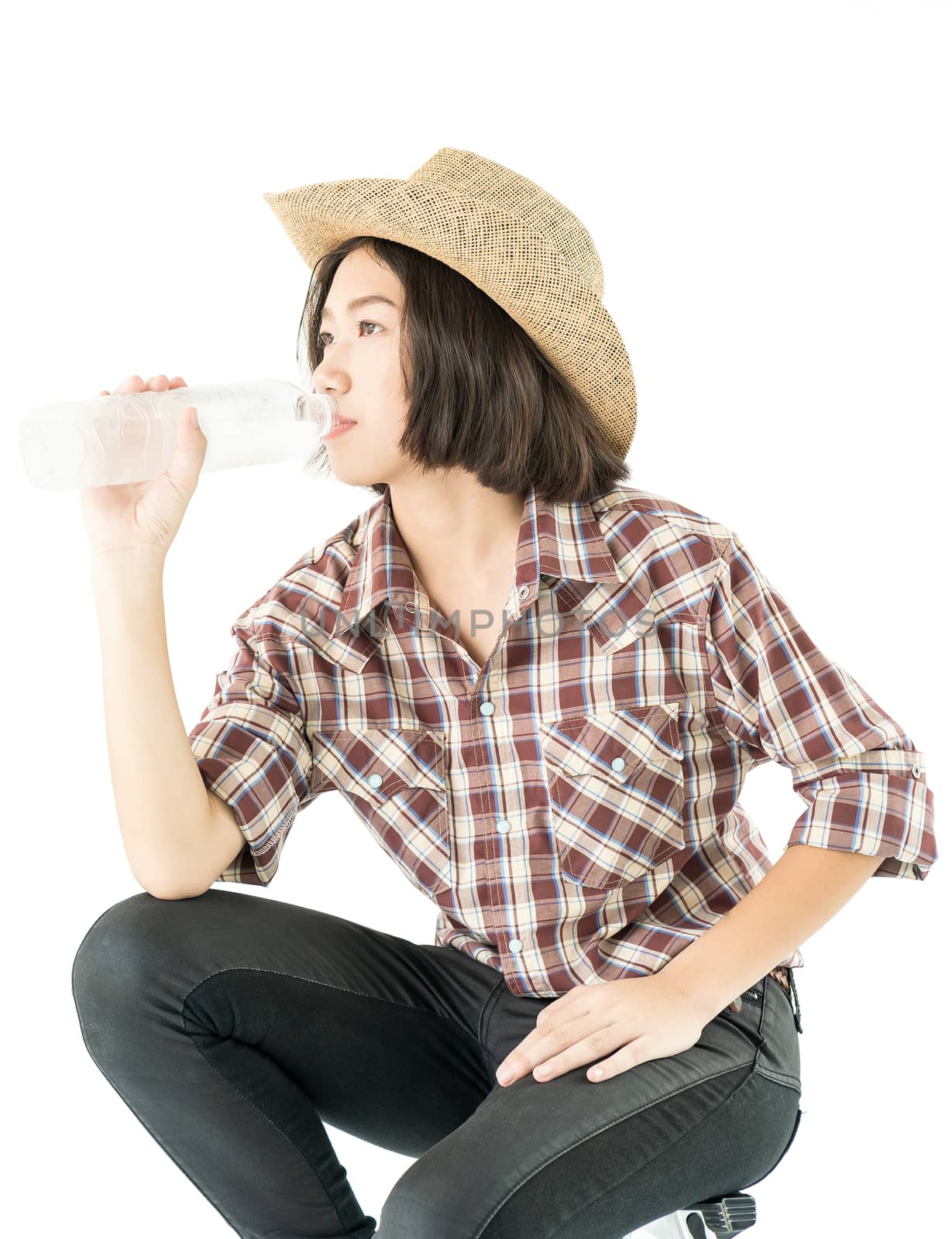 Young pretty woman in a cowboy hat and plaid shirt holding a water bottle isolated on white background