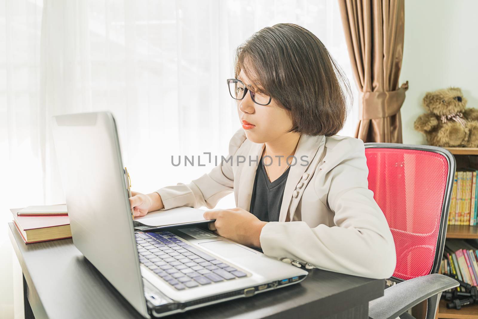 Woman teenage short hair in smart casual wear working on laptop while sit near window in home office