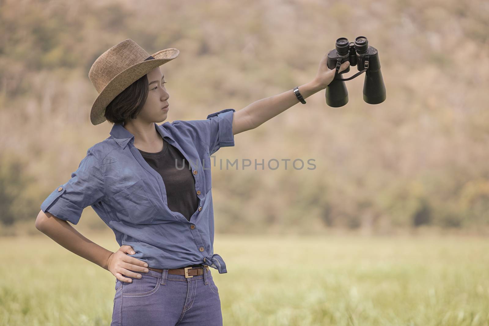 Woman wear hat and hold binocular in grass field by stoonn