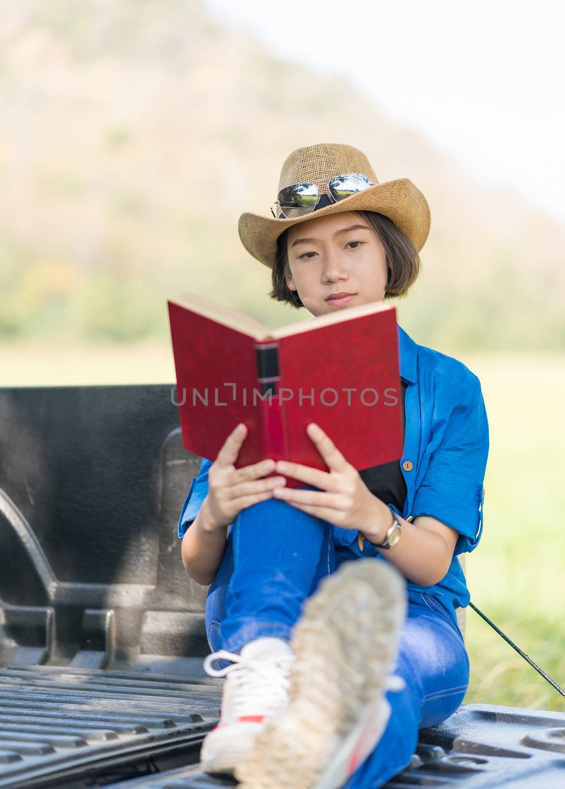 Woman wear hat and reading the book on pickup truck by stoonn