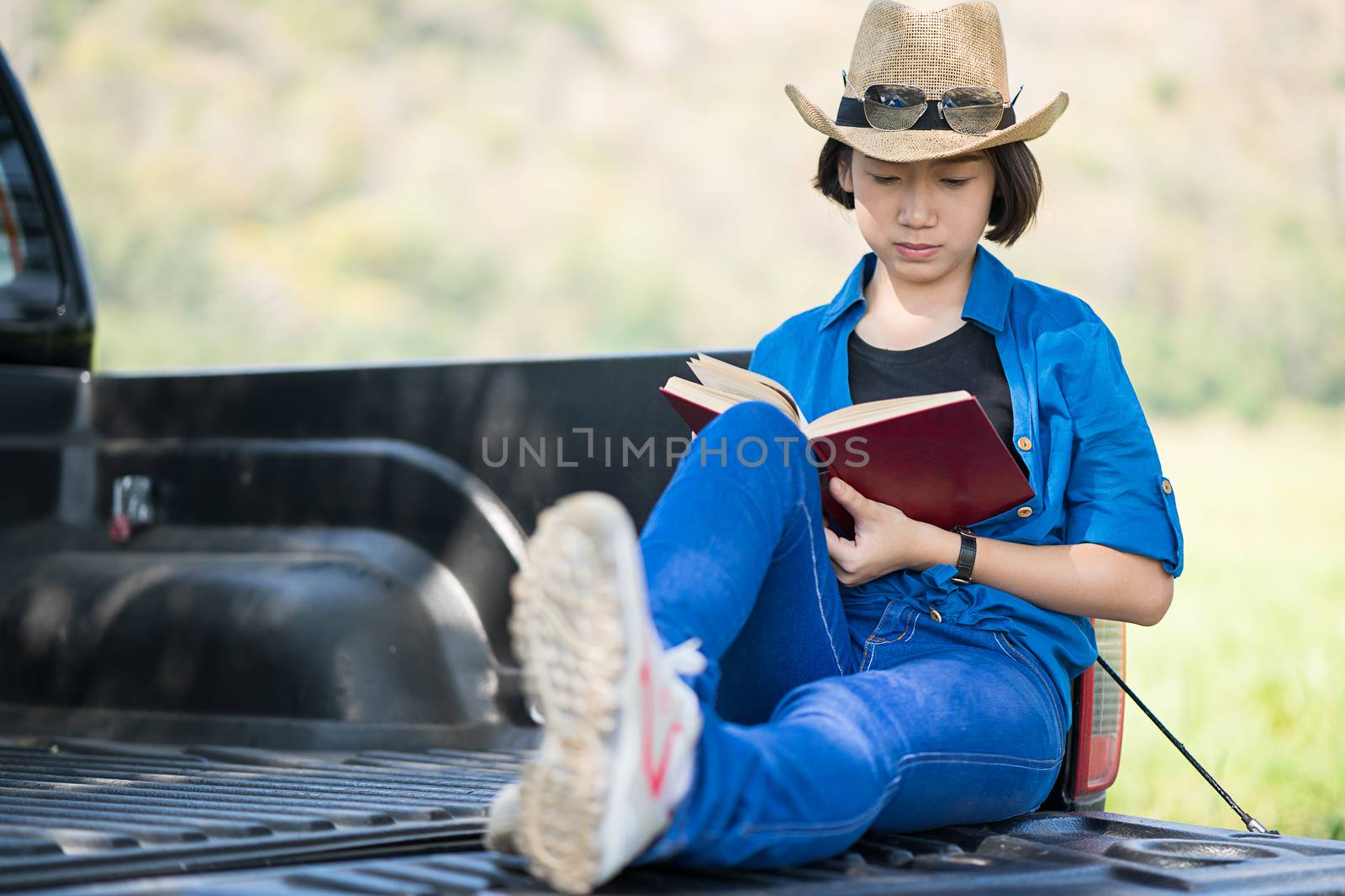 Woman wear hat and reading the book on pickup truck by stoonn