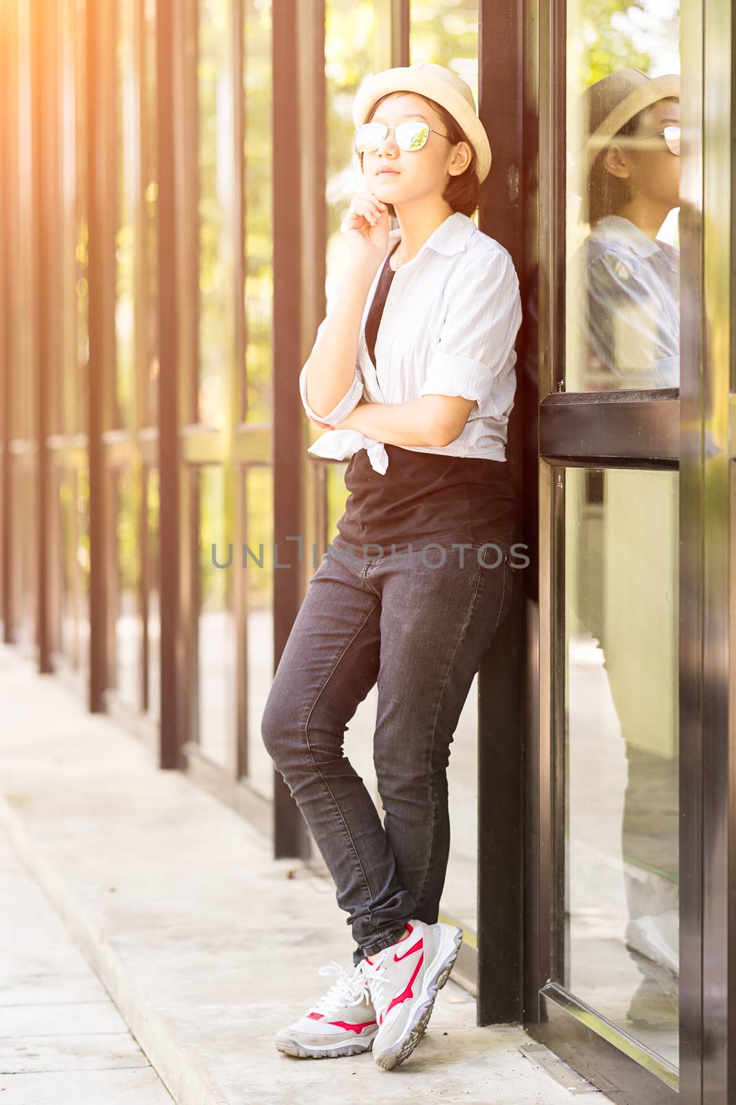 Women wearing hat standing in front of a glass building by stoonn