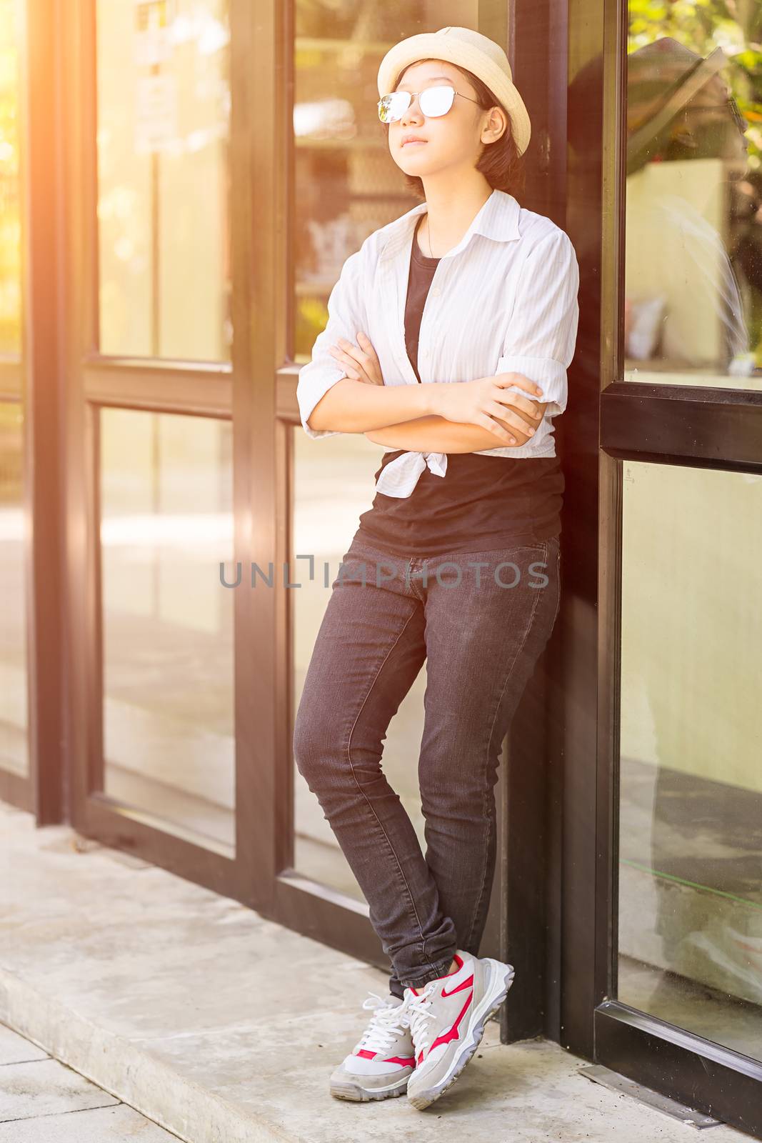 Women wearing hat standing in front of a glass building by stoonn