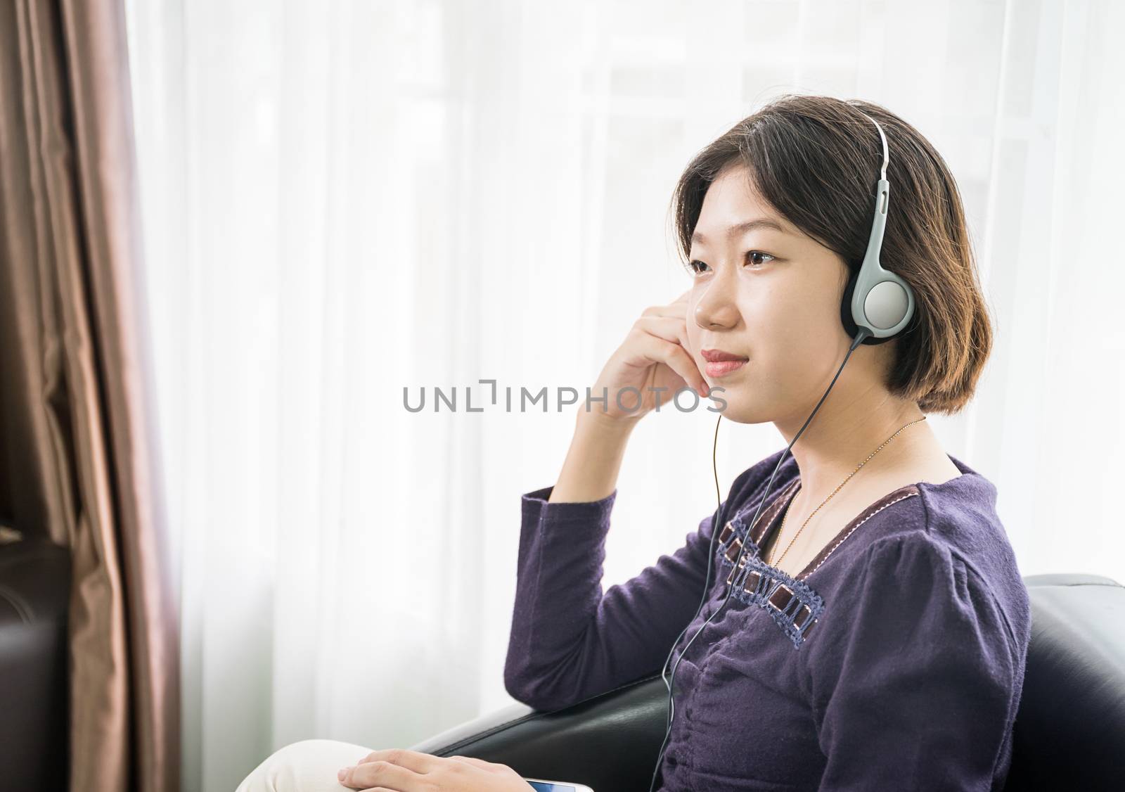 Young asian woman short hair listening music in living room by stoonn