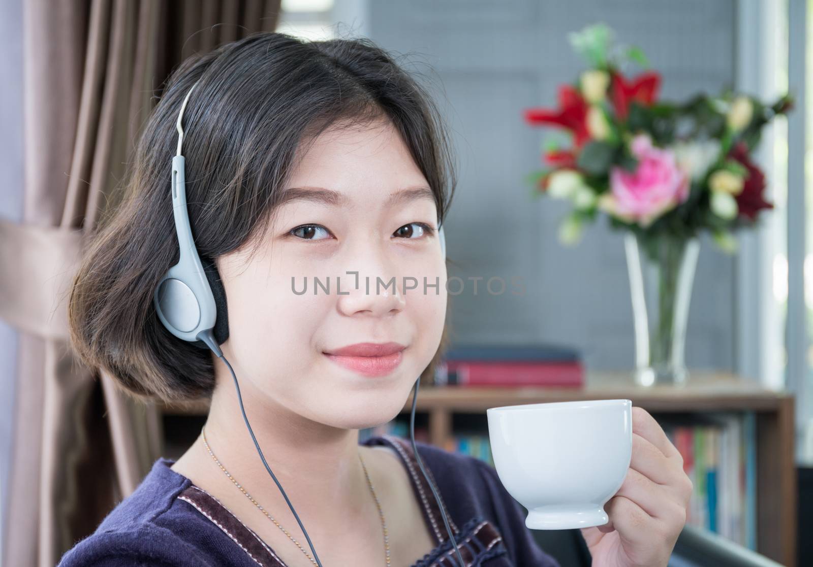 Close up beautiful young asian woman short hair listening music in living room at home