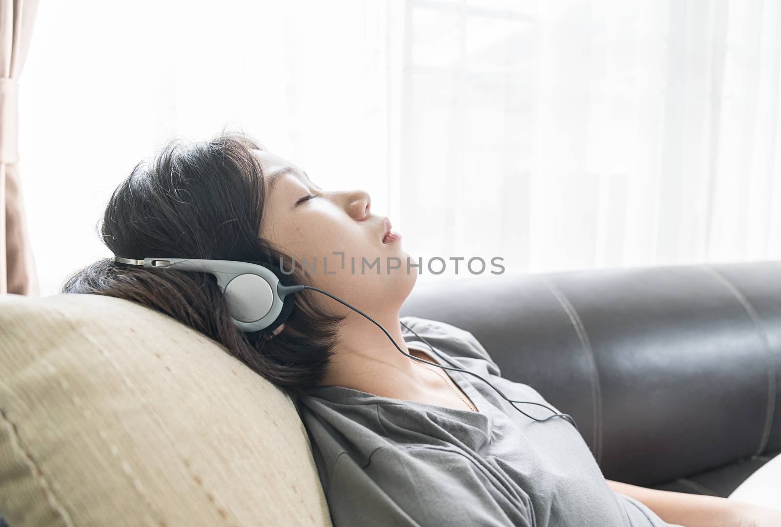 Close up beautiful young asian woman short hair listening music on the couch at home