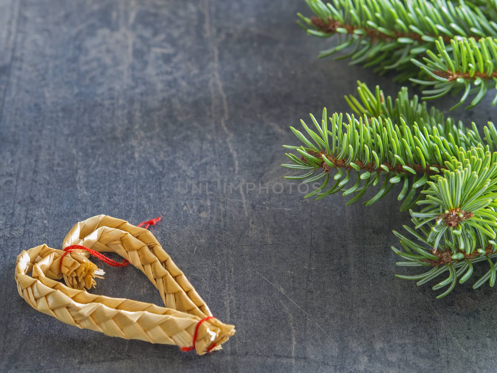 vertical christmas decoration frame fir branch and straw heart on gray texture background