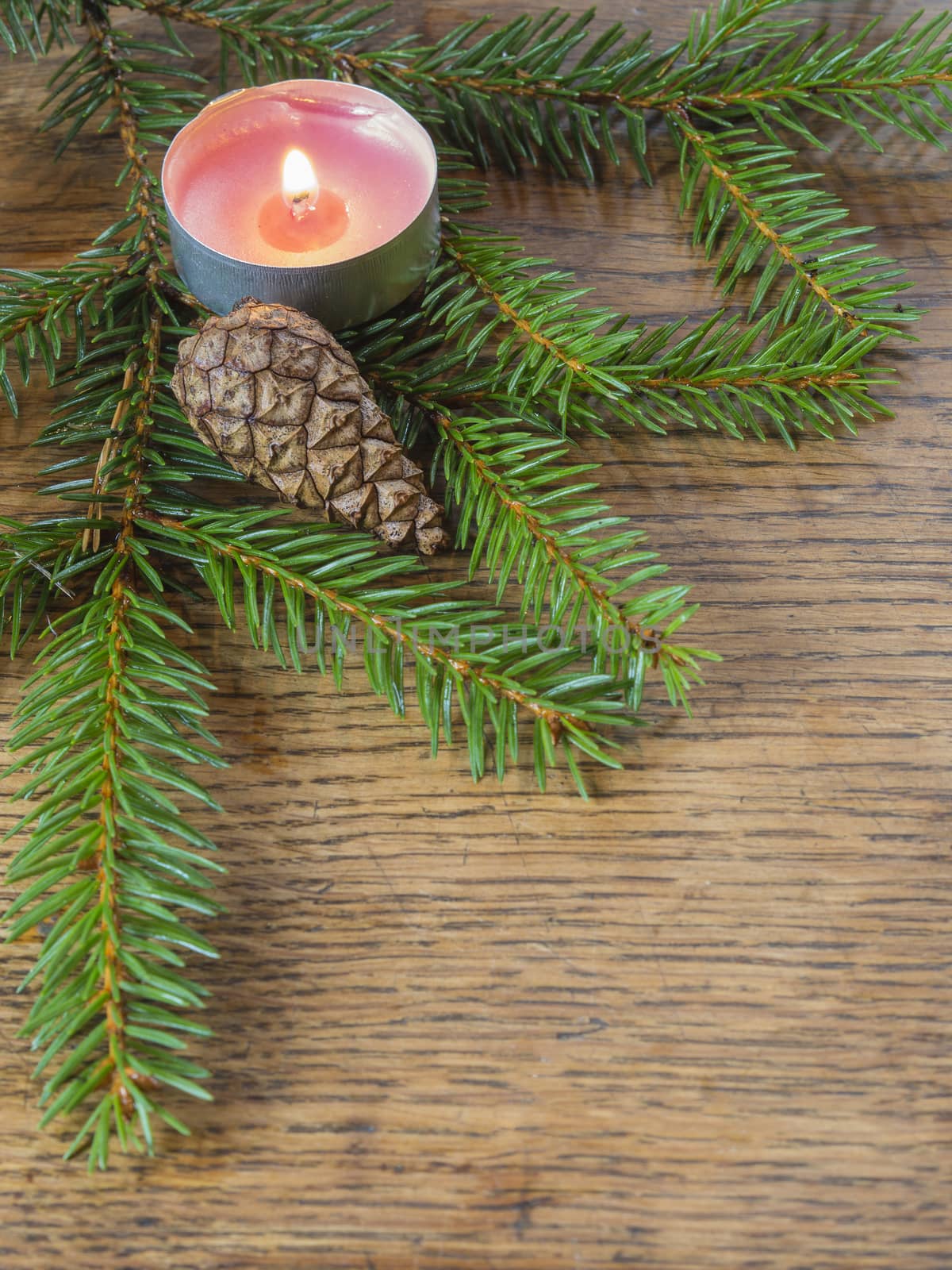 vertical christmas decoration frame spruce tree fir branch with cone and tea light candle on old wooden desk background