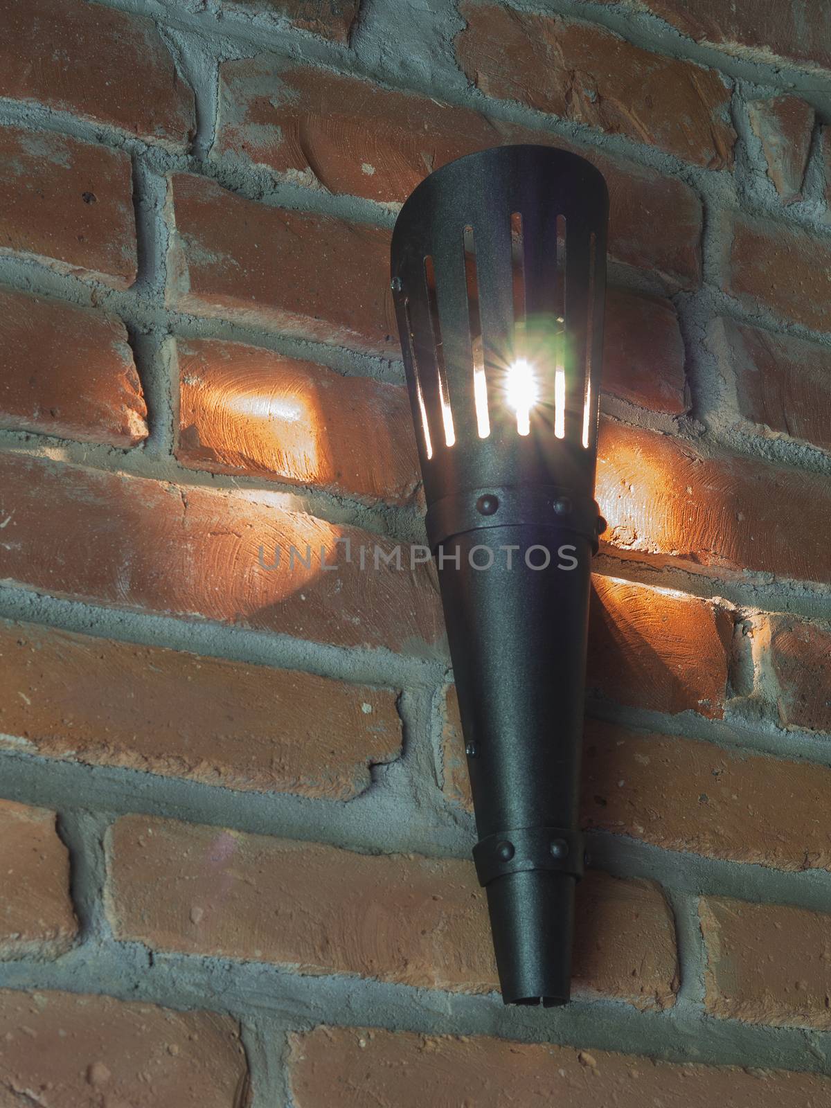black iron electric torch light on the red brick wall background by Henkeova