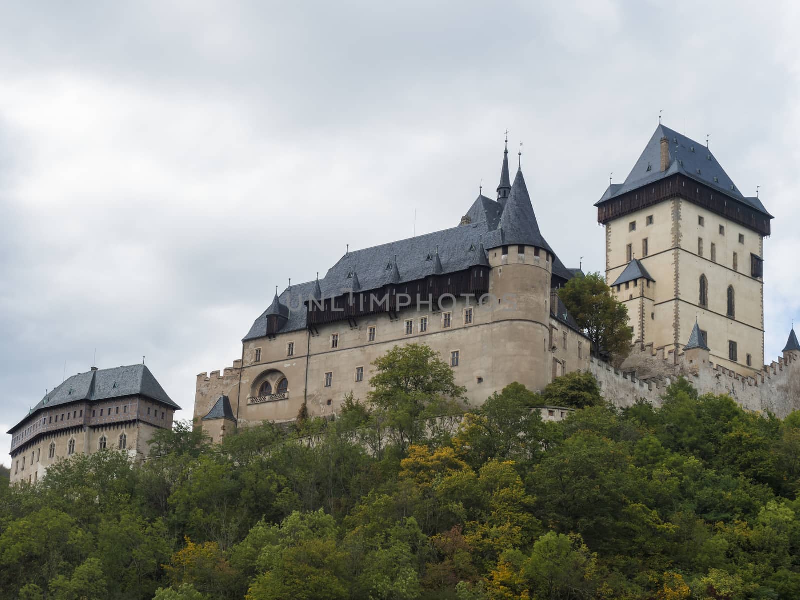 Close up Karlstejn gothic state castle near Prague, the most famous castle in Czech Republic with autumn colored trees. Blue sky clouds background. Located near Prague