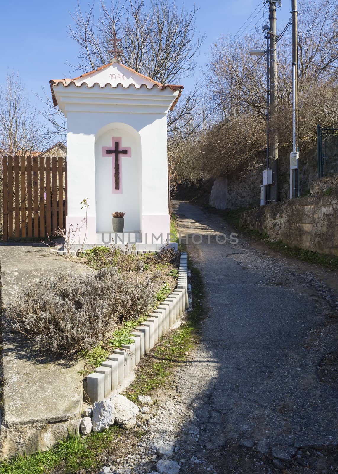 small white wayside shrine, road blessing or Gods torture with cross next village road curve in Srbsko, Czech republic by Henkeova