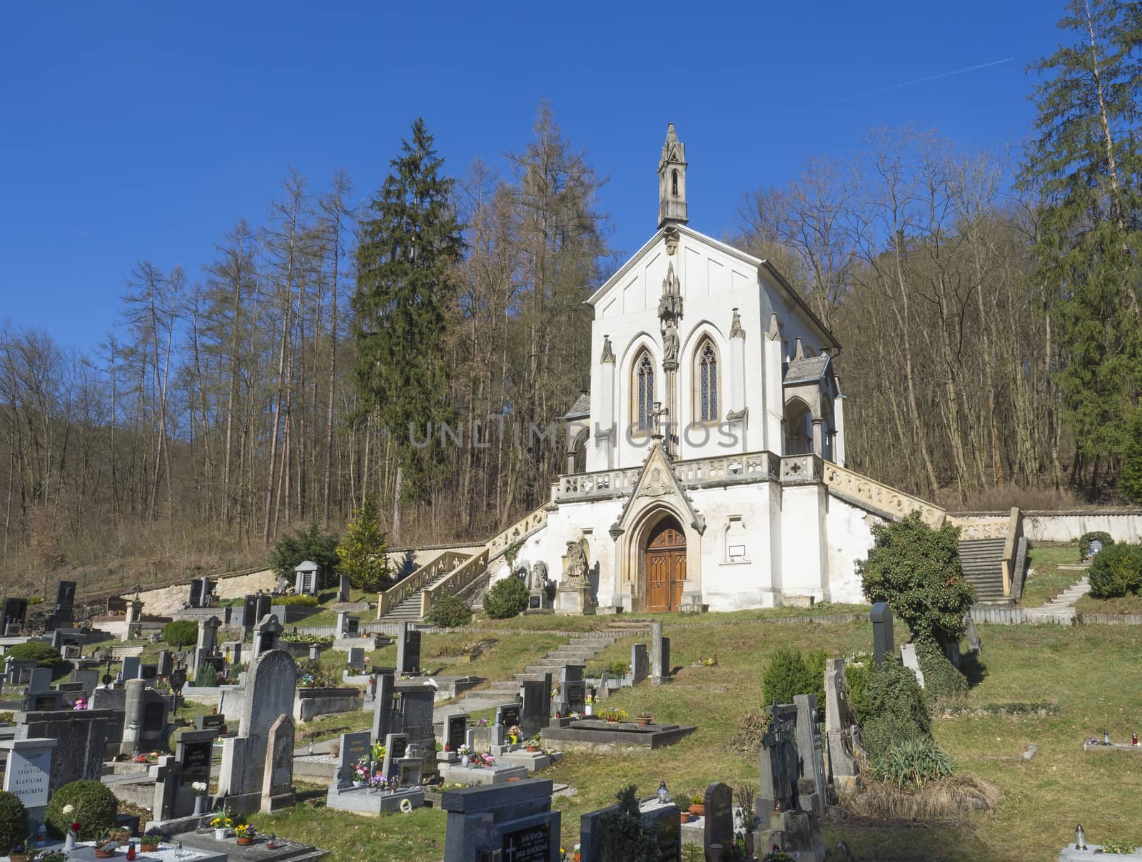 Saint Maximilian Chapel, baroque church with old cemetery in Saint John under the Cliff, Svaty Jan pod Skalou, Czech Republic, spring sunny day, blue sky.
