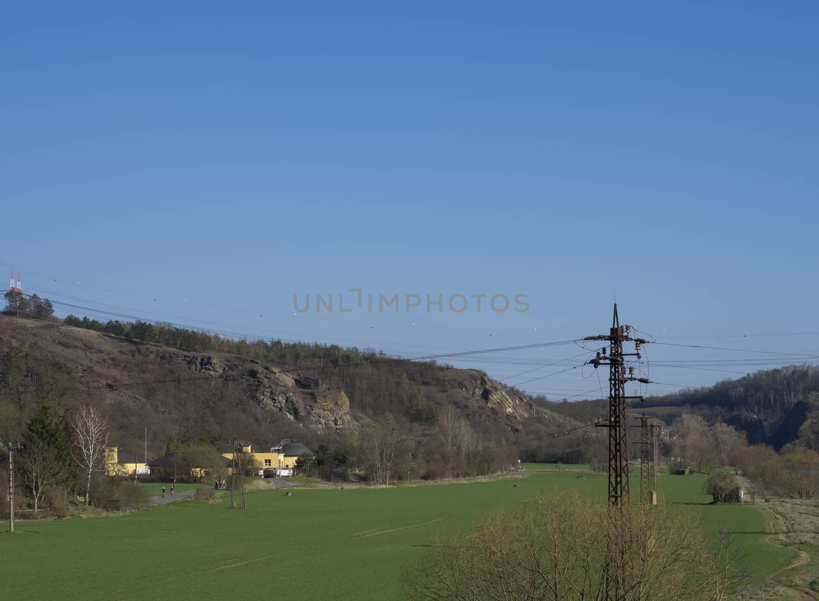 Green meadow and rocks in city Beroun, early spring, blue sky. Czech Republic.