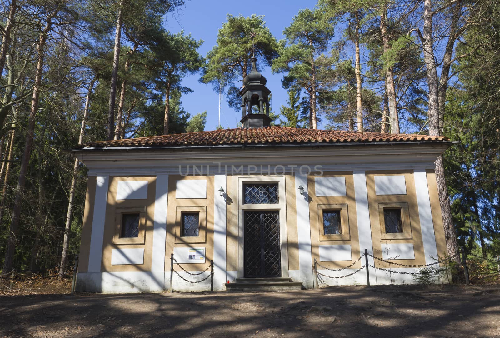 small chapel in baroque monastery Skalka on  sunny day early spring, green pine tree and blue sky background