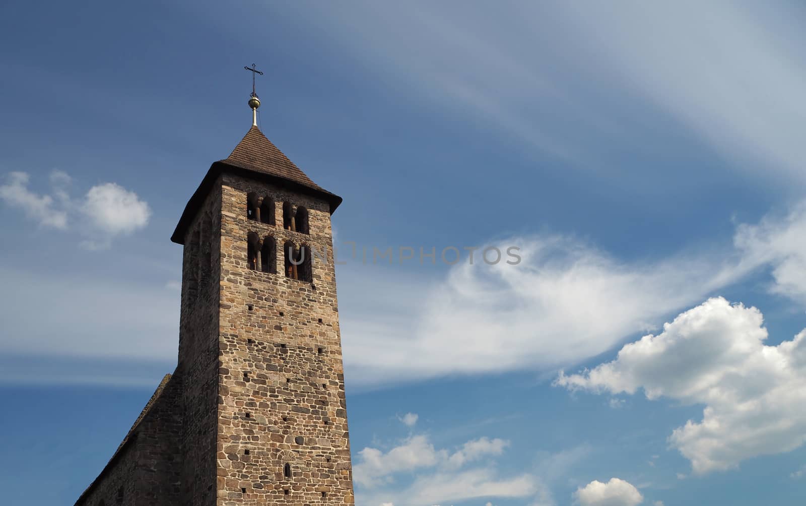 old stone church tower on the ramatic blue clouds background