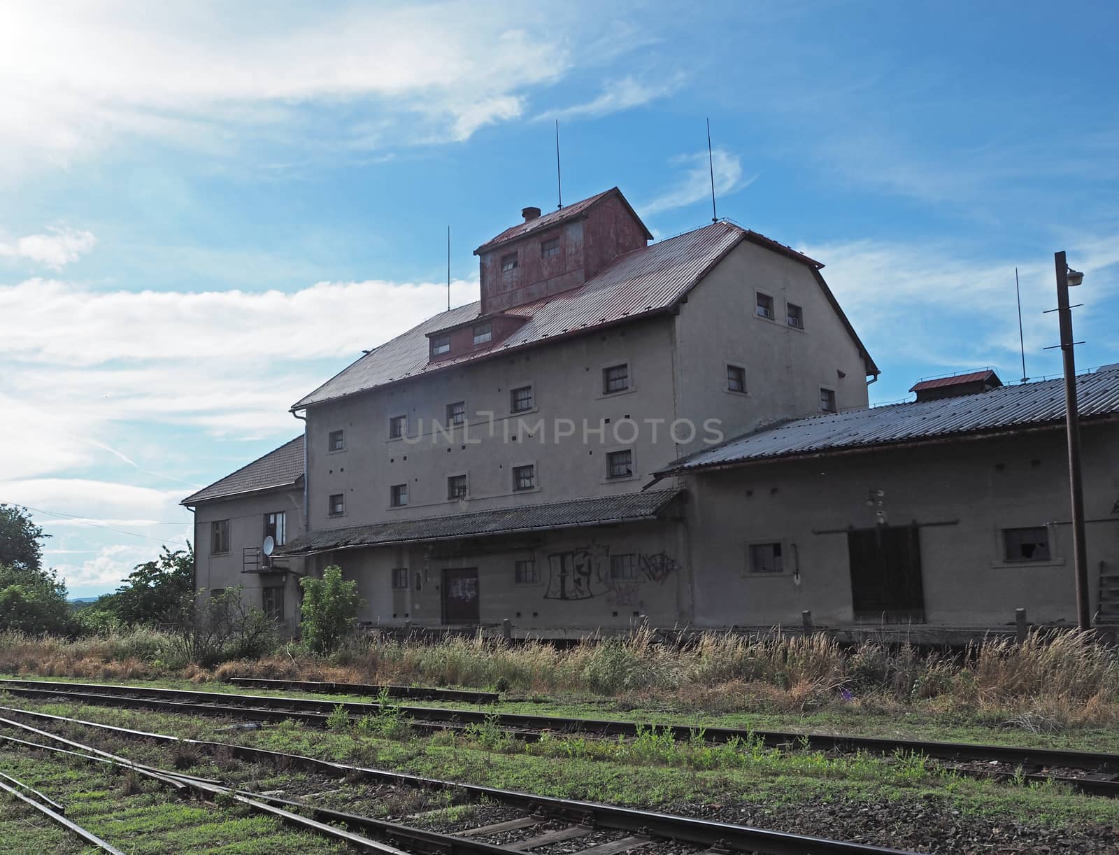 old empty house on railway with graffiti, train line and blue sky