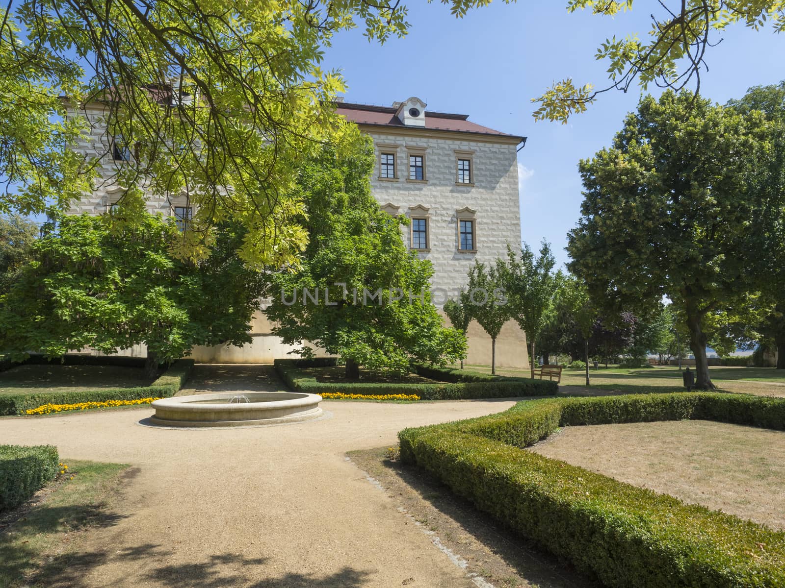 Renaissance style castle with Sgraffito decorated facade, park, footpath, green trees garden, fountain and wooden bench, sunny summer day by Henkeova