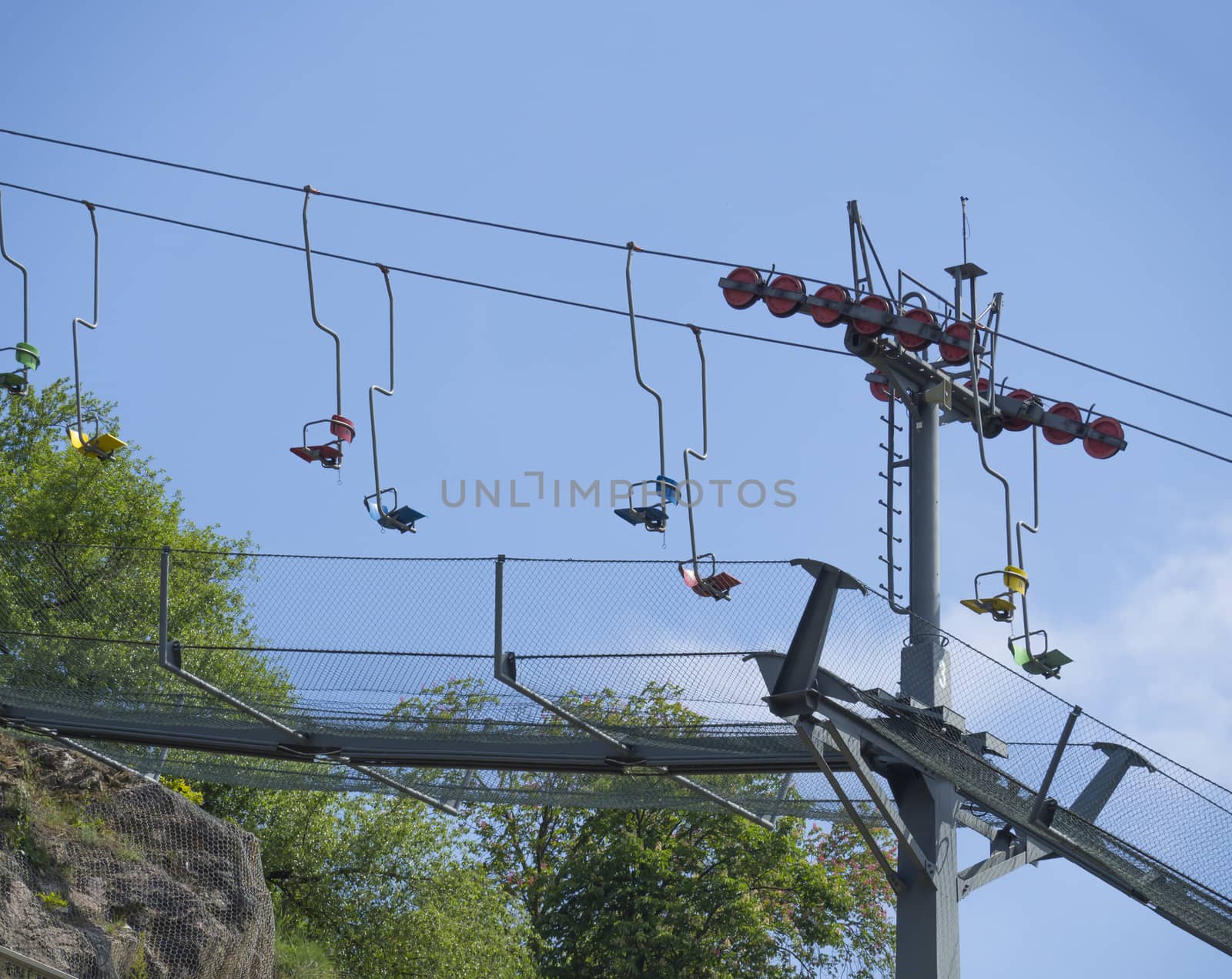 Empty colorful old chair lift, funicular, in Prague ZOO and cable car. Blue sky background. by Henkeova