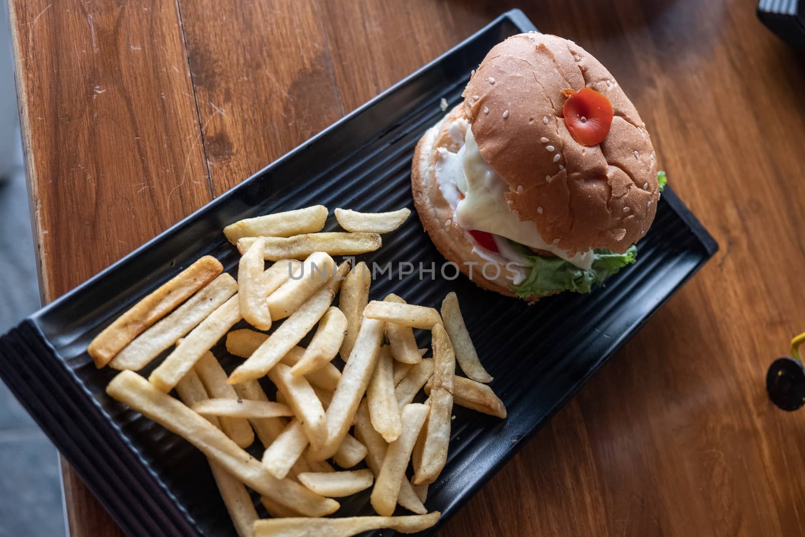 Tasty hamburger with french fries on wooden table