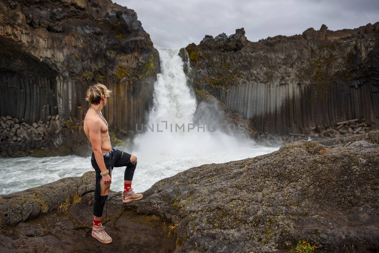 Shirtless and muscular boy looks at the Aldeyjarfoss waterfall in Iceland by nickfox