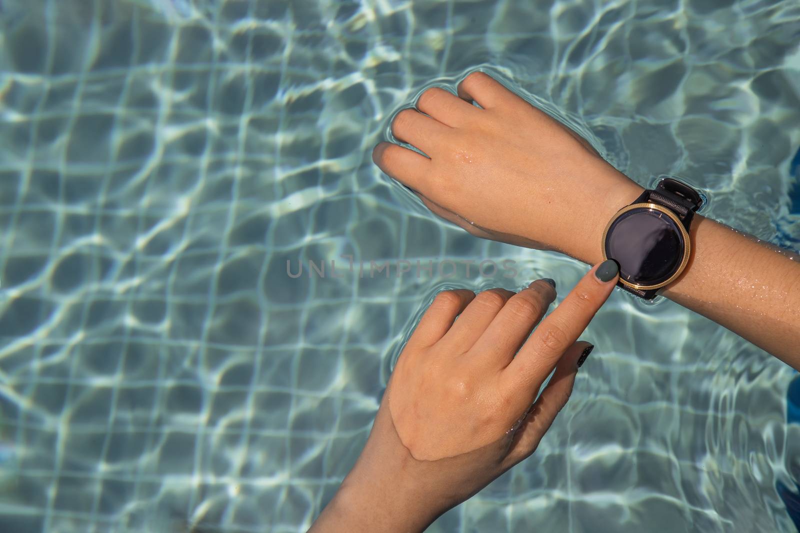 Female using hands with the smart watch at the pool by tosirikul