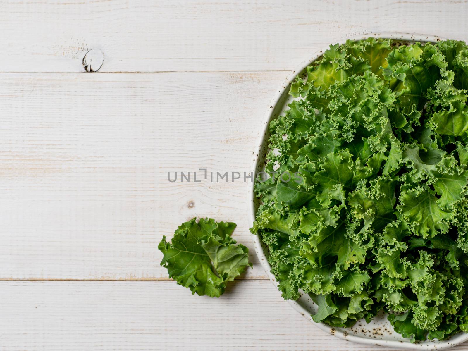 Kale leaves in bowl, copy space, top view by fascinadora